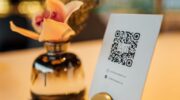 Табличка с QR-кодом на столе рядом с вазой
