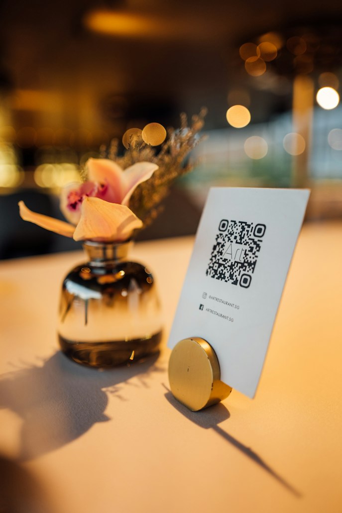Табличка с QR-кодом на столе рядом с вазой